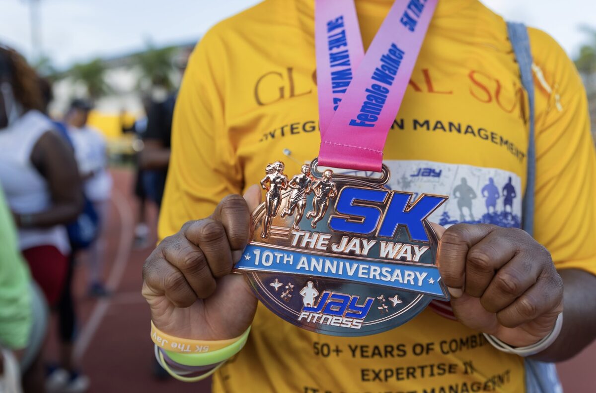 A participant holds the 10th Anniversary 5K The Jay Way finisher medal